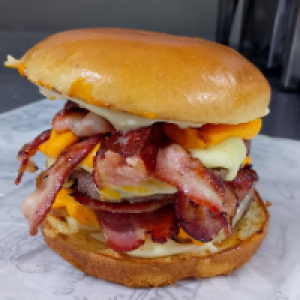 PÃO BRIOCHE,  MAIONESE,  2 CARNES ARTESANAL 180G,  QUEIJO MUSSARELA,  QUEIJO CHEDDAR CREMOSO,  CEBOLA CARAMELIZADA,  FATIAS DE BACON DEFUMADO. ACOMPANHA FRITAS.