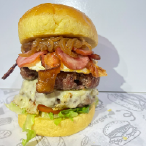 Pão brioche selado na manteiga,  duas suculentas carnes de 100g cada feitas na brasa,  salada fresca com tomate e alface,  cebola caramelizada,  generosas fatias de calabresa,  bacon torradinho,  ovo frito e muito queijo!