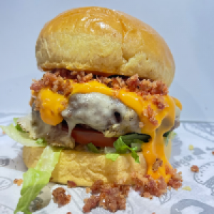 Pão Brioche,  carne de 180g, salada fresca,  queijo,  farofa de Bacon e muito cheddar.