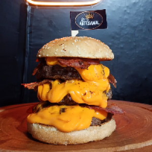 Pão gergelim,  3x carne de 150g,  cebola caramelizada,  3x cheddar creme e 3x bacon.
Foto real do lanche!