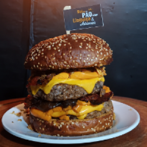 pão gergelim especial,  2x carne bovina 200g,  2x duplo cheddar (fatia + creme),  2x bacon e cebola crispy.
Foto real do lanche!